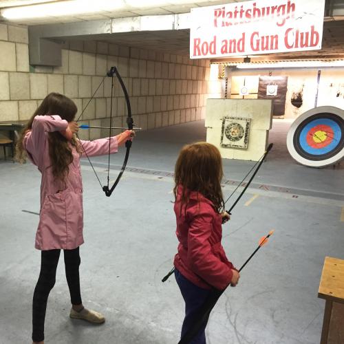 Two youth members shooting in the indoor archery range